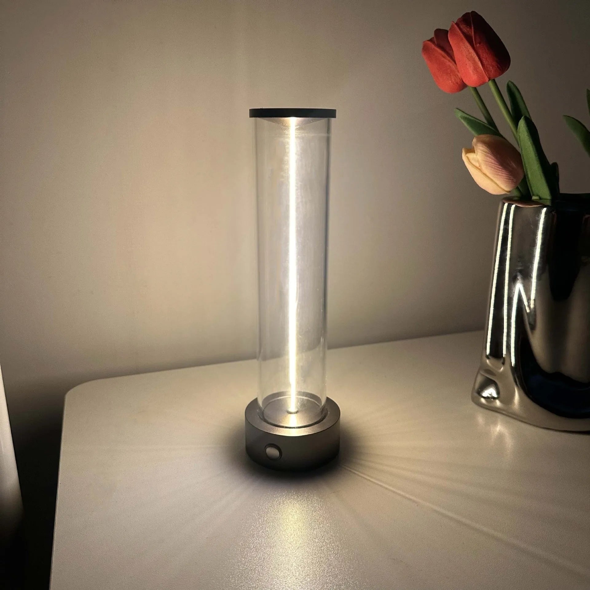 Tall cylindrical frosted glass USB rechargeable LED night light with a magnetic base on a wooden surface.