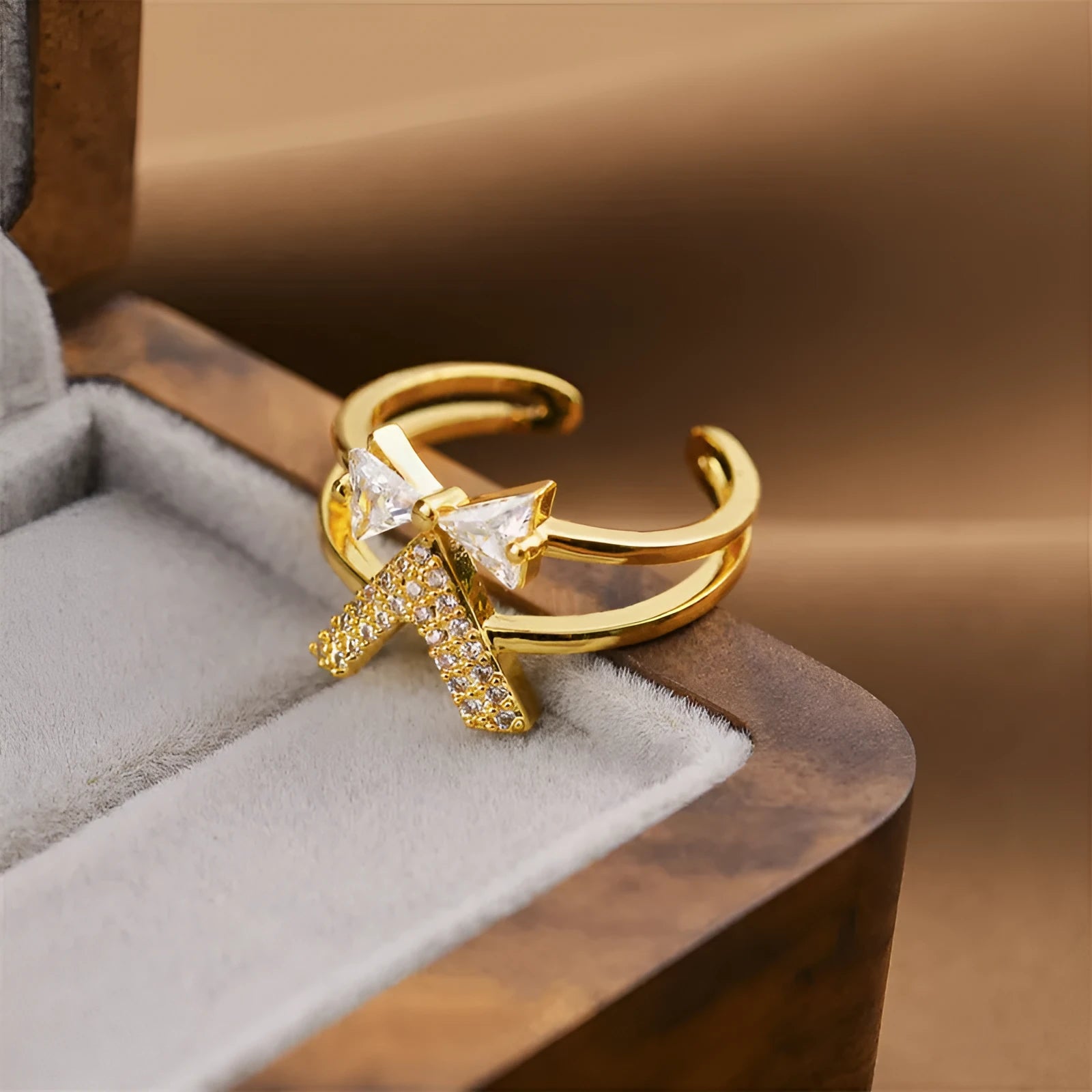 Gold electroplated geometric women's ring with an open adjustable design on a plain background