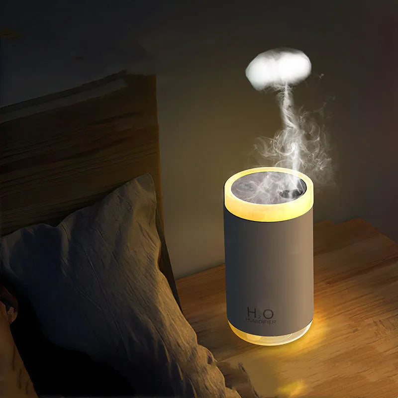 White USB humidifier emitting jellyfish-shaped smoke ring mist with warm night light glow on a desk.
