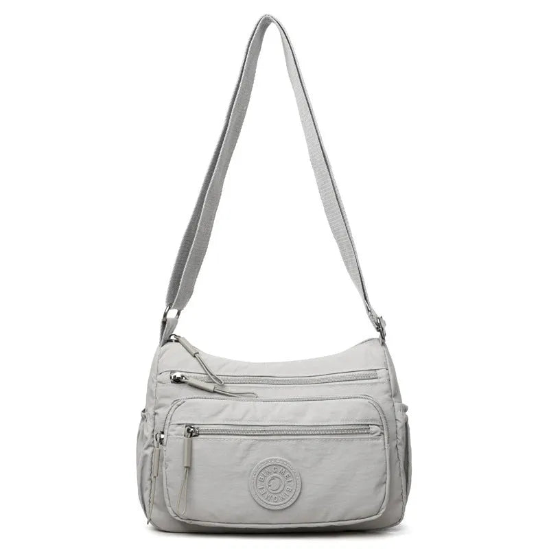 Grey water-repellent nylon crossbody bag showing outer pocket and internal organiser compartments.