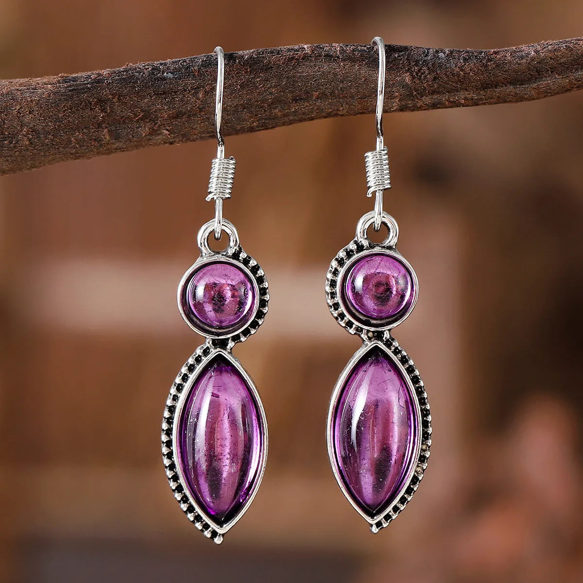 A pair of vintage geometric bohemian pendant earrings in black and purple with round design elements.