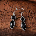 A pair of vintage geometric bohemian pendant earrings in black and purple with round design elements.