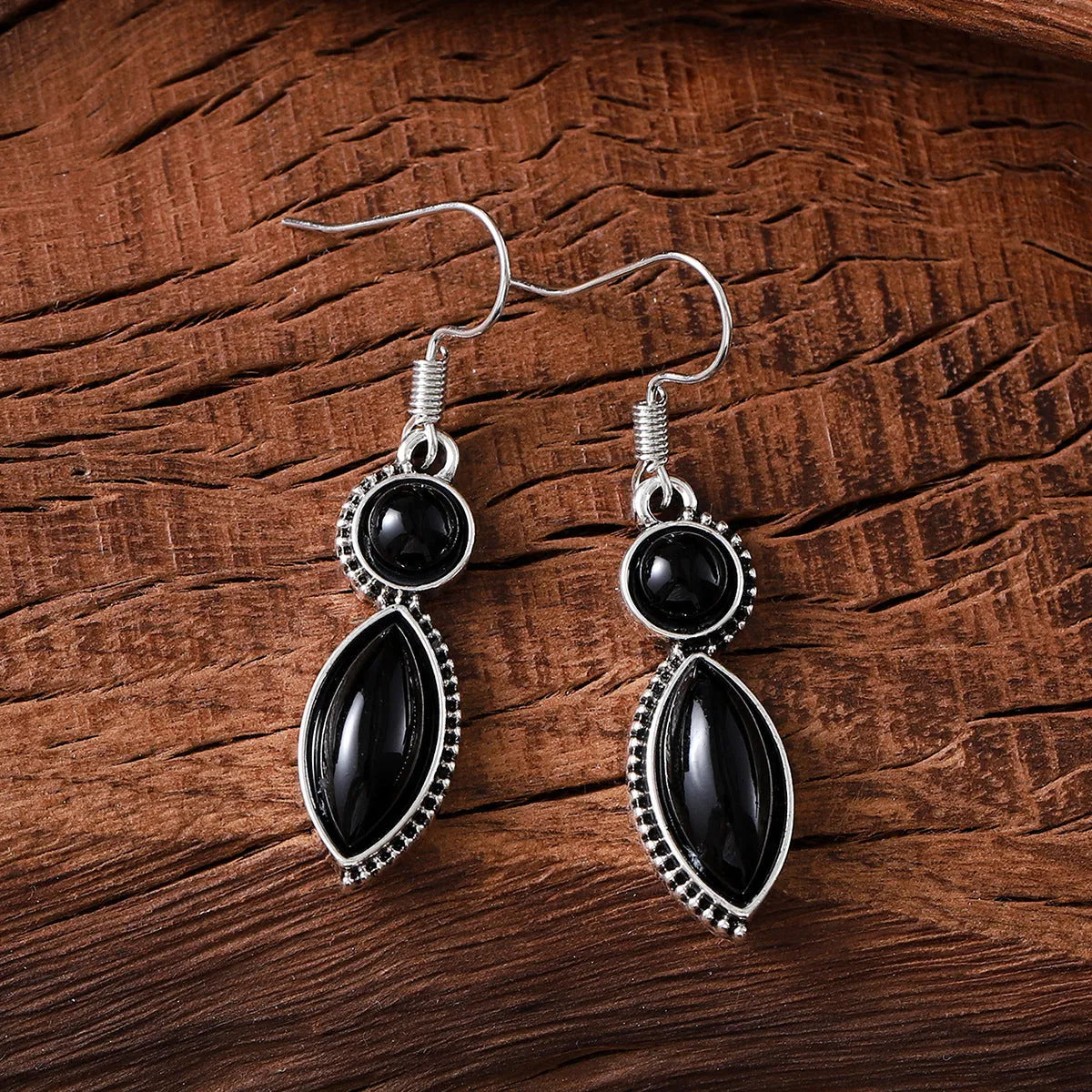 A pair of vintage geometric bohemian pendant earrings in black and purple with round design elements.