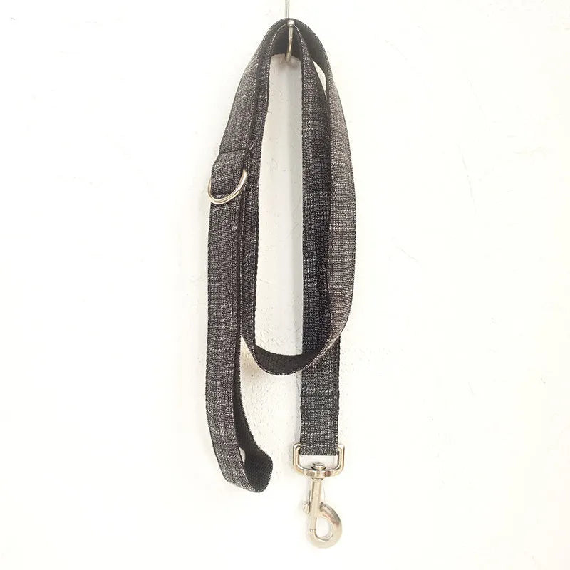 Black polyester padded dog collar with light gold trim and matching lead on a light surface