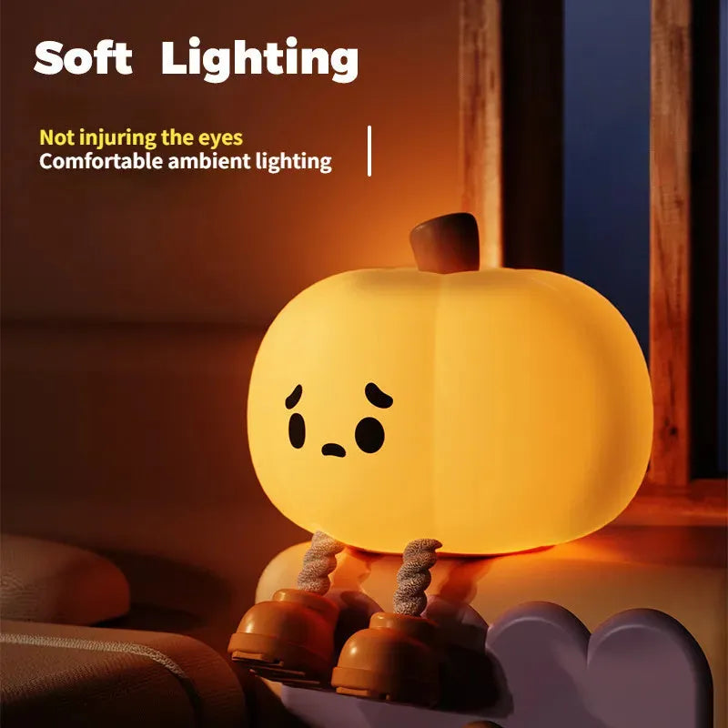 Soft orange pumpkin-shaped silicone night light with a warm glow, showing its compact size on a table.