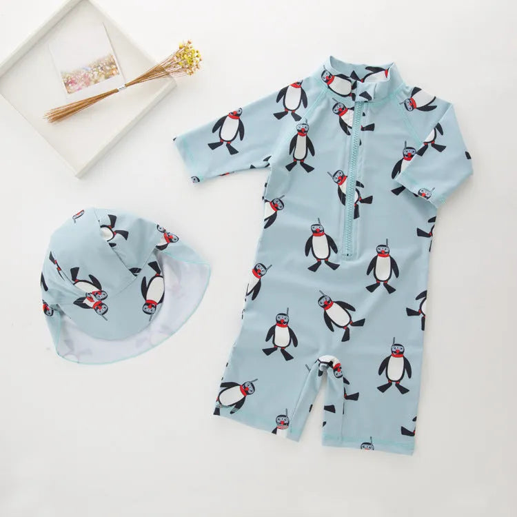 Boys' blue and white penguin print long sleeve swimsuit with matching swimming cap laid flat.