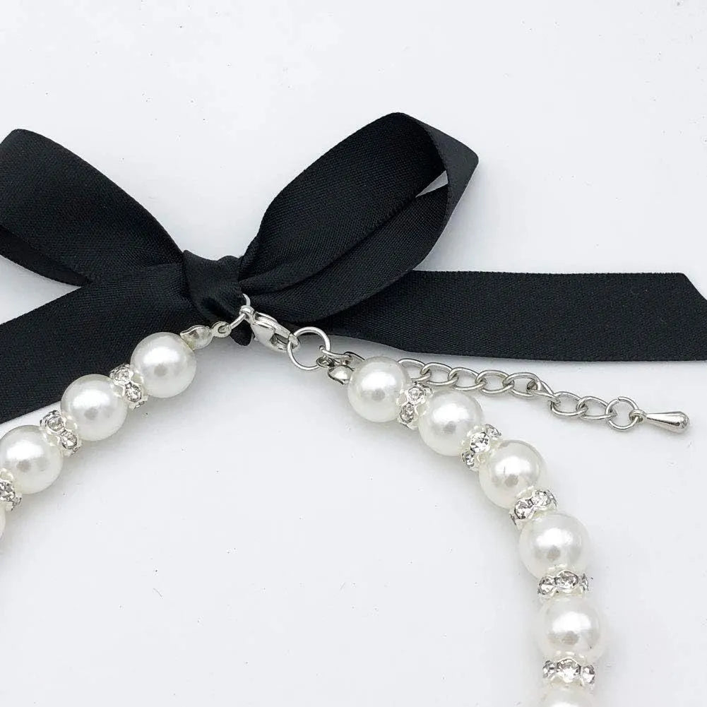 Small dog wearing adjustable diamond pearl necklace with rhinestones and ribbon bow in blue colour