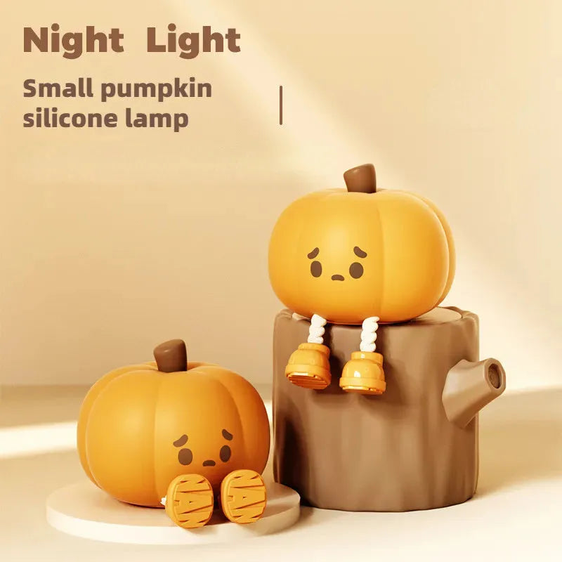 Soft orange pumpkin-shaped silicone night light with a warm glow, showing its compact size on a table.