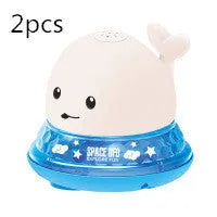White and blue whale-shaped bath toy spraying water with LED lights on, floating in a baby bath