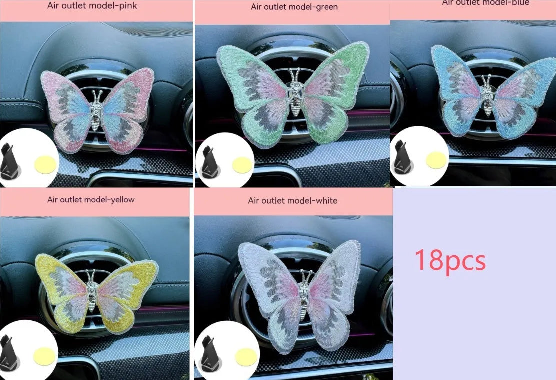 Fabric embroidered butterfly car air vent decoration in multiple colour options on a dashboard.