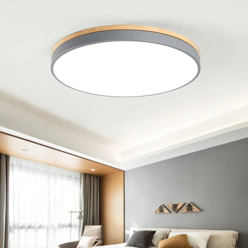 Round Scandinavian style wood and iron LED ceiling lamp with a white acrylic shade on a white ceiling.