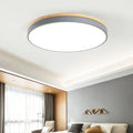 Round Scandinavian style wood and iron LED ceiling lamp with a white acrylic shade on a white ceiling.