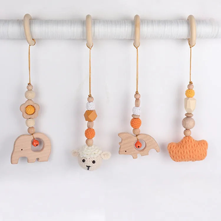 Beech wood baby rattle with animal pendants in orange, 28cm length, on white background