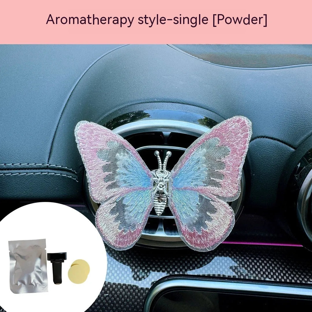 Fabric embroidered butterfly car air vent decoration in multiple colour options on a dashboard.