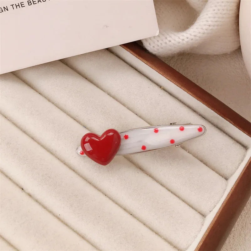 Red love heart-shaped plastic hair clip with retro dots and a willow leaf silhouette on a white background.