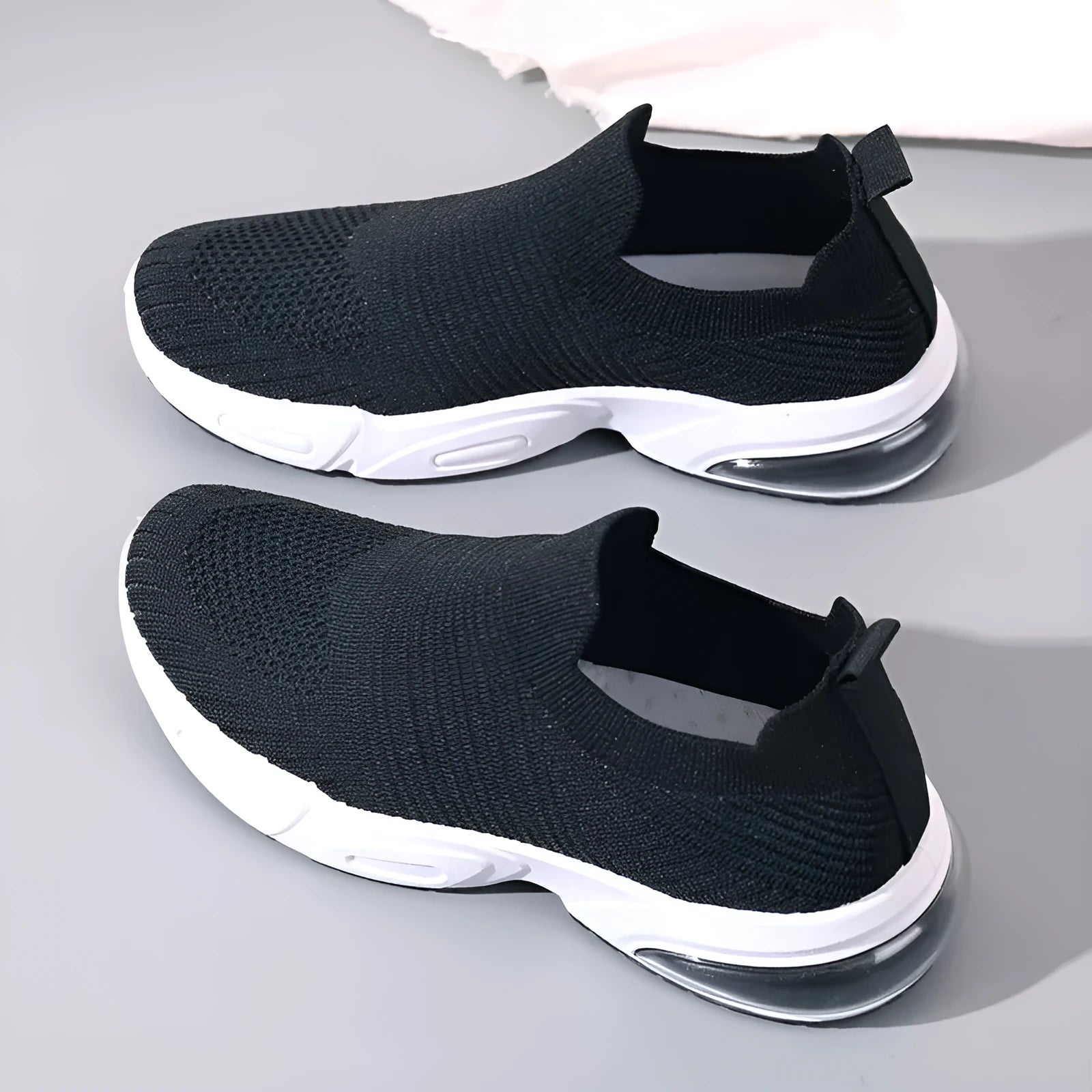 A pair of low-top slip-on sock shoes with a mesh upper and PVC sole on a plain background.