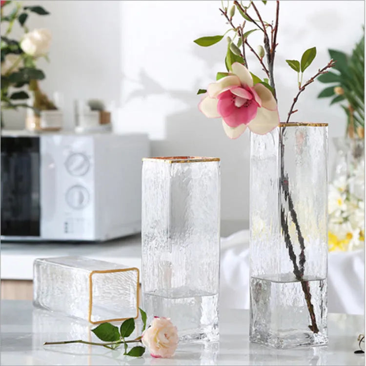 Transparent gold-painted glass vase on table with flower stems, 8x30cm size