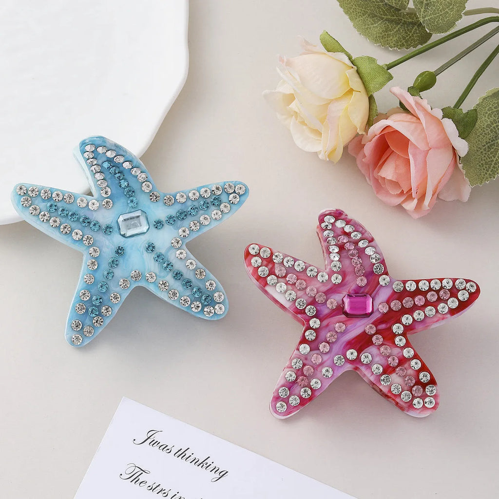 Blue acrylic starfish hairpin with diamond-encrusted surface on white background