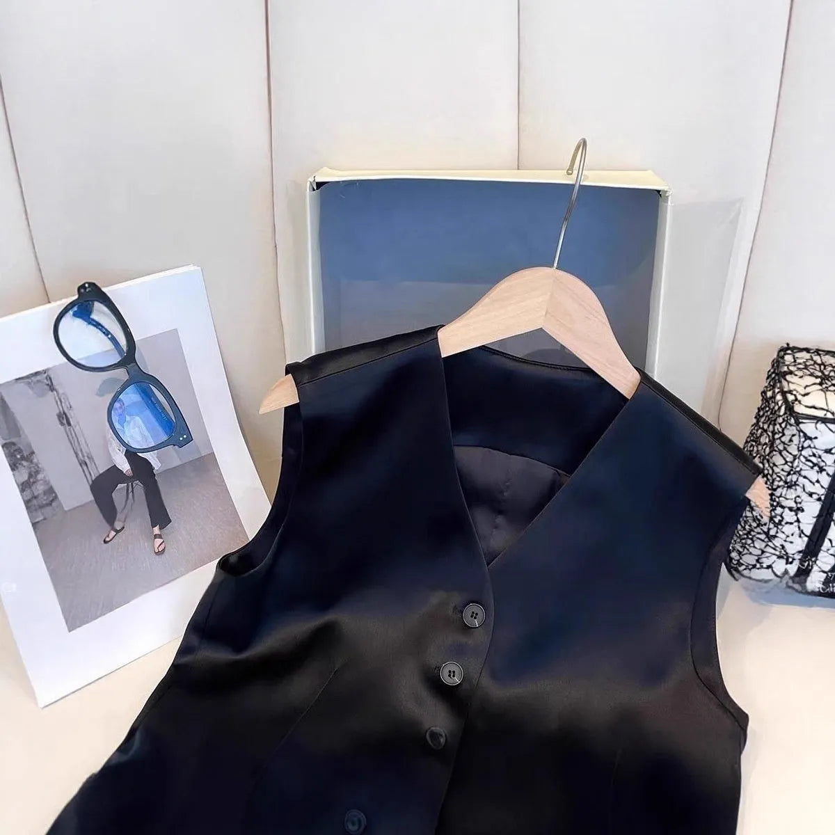 Black satin ladies sleeveless vest with loose fit on a hanger