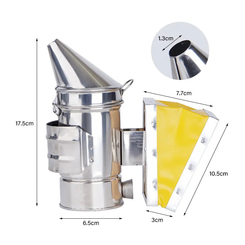 Stainless steel bee smoker with leather bellow on a wooden table against a blurred outdoor background