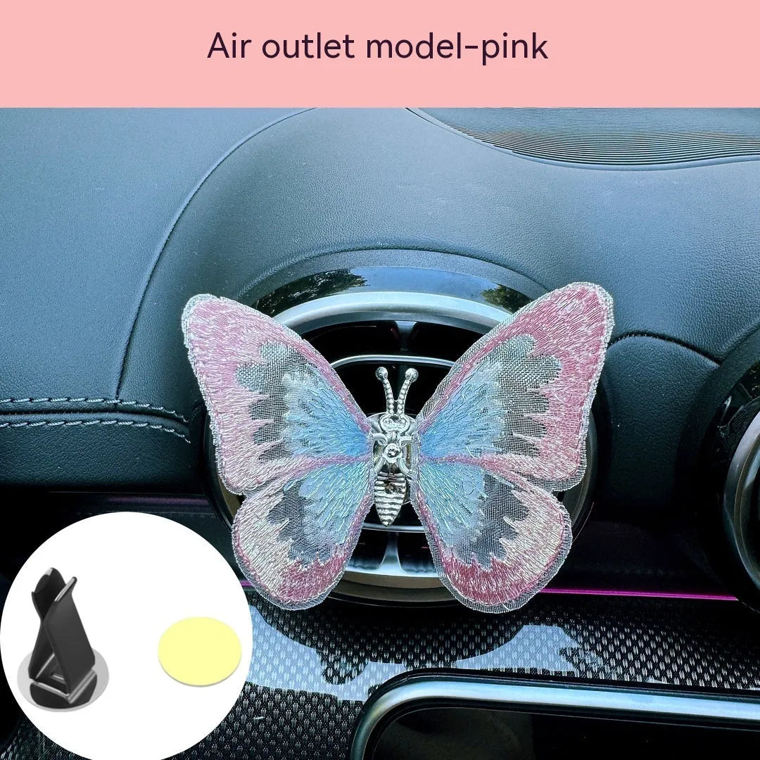 Fabric embroidered butterfly car air vent decoration in multiple colour options on a dashboard.