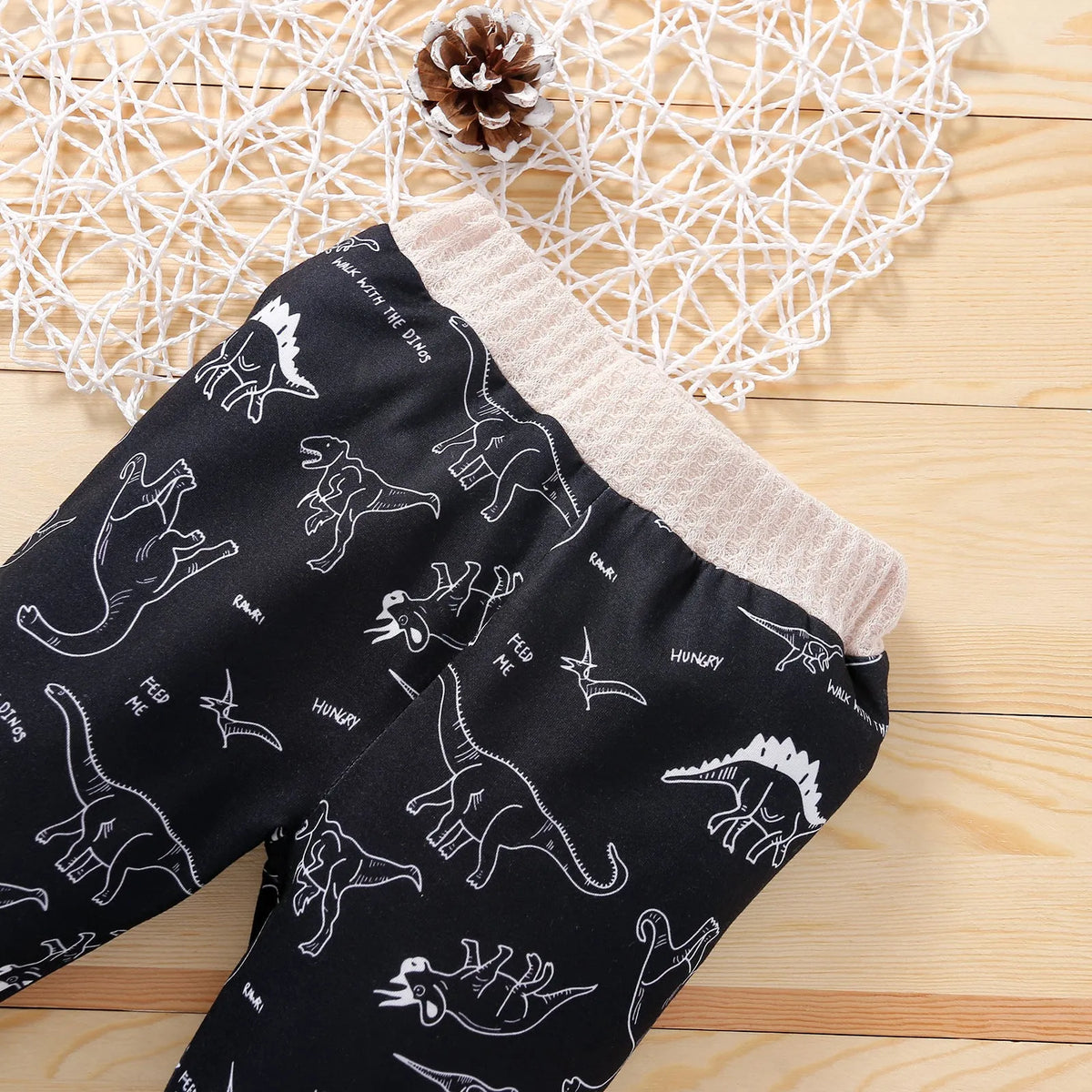 Cotton children's pants suit with dinosaur cartoon pattern in beige, pullover top and trousers set on child model