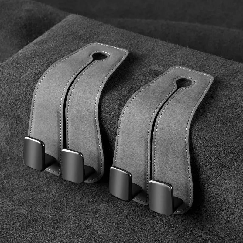 Black suede and metal car seat hook organiser hanging on a car headrest.