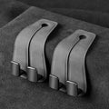 Black suede and metal car seat hook organiser hanging on a car headrest.