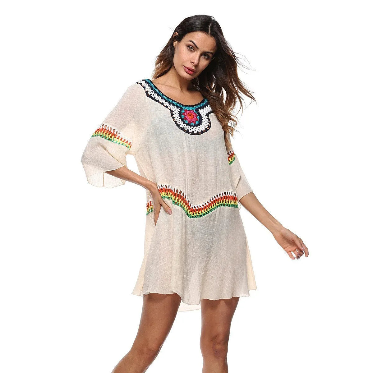 Woman wearing a crocheted white sun protection beach cover-up by the water.