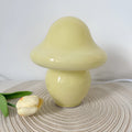 Glass mushroom decorative lamp with three-colour light in orange smooth finish on a wooden table