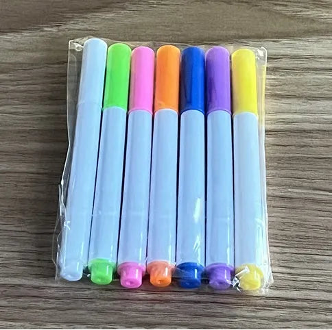 DIY acrylic LED message board lamp on a desk with colourful writing, showing USB cable and pens.