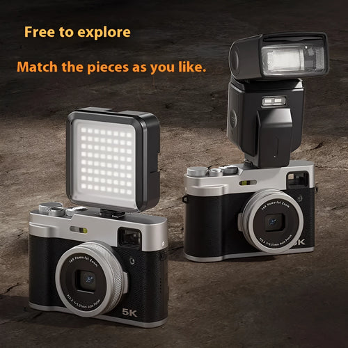 Black or brown 5K HD digital camera with dual lenses and an optical viewfinder on a table.