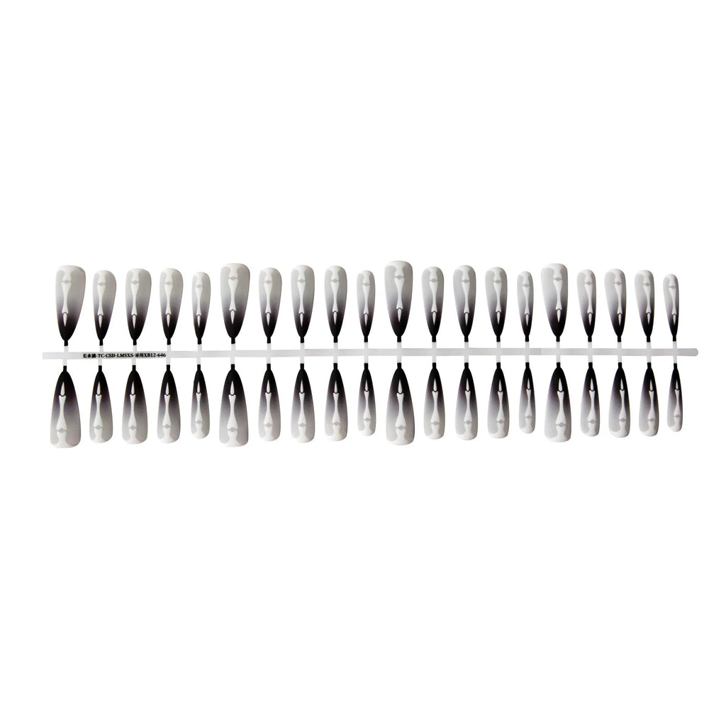 Close-up of long black and pink Christmas gothic nail tips with frosted finish on a flat surface, next to a storage strip.