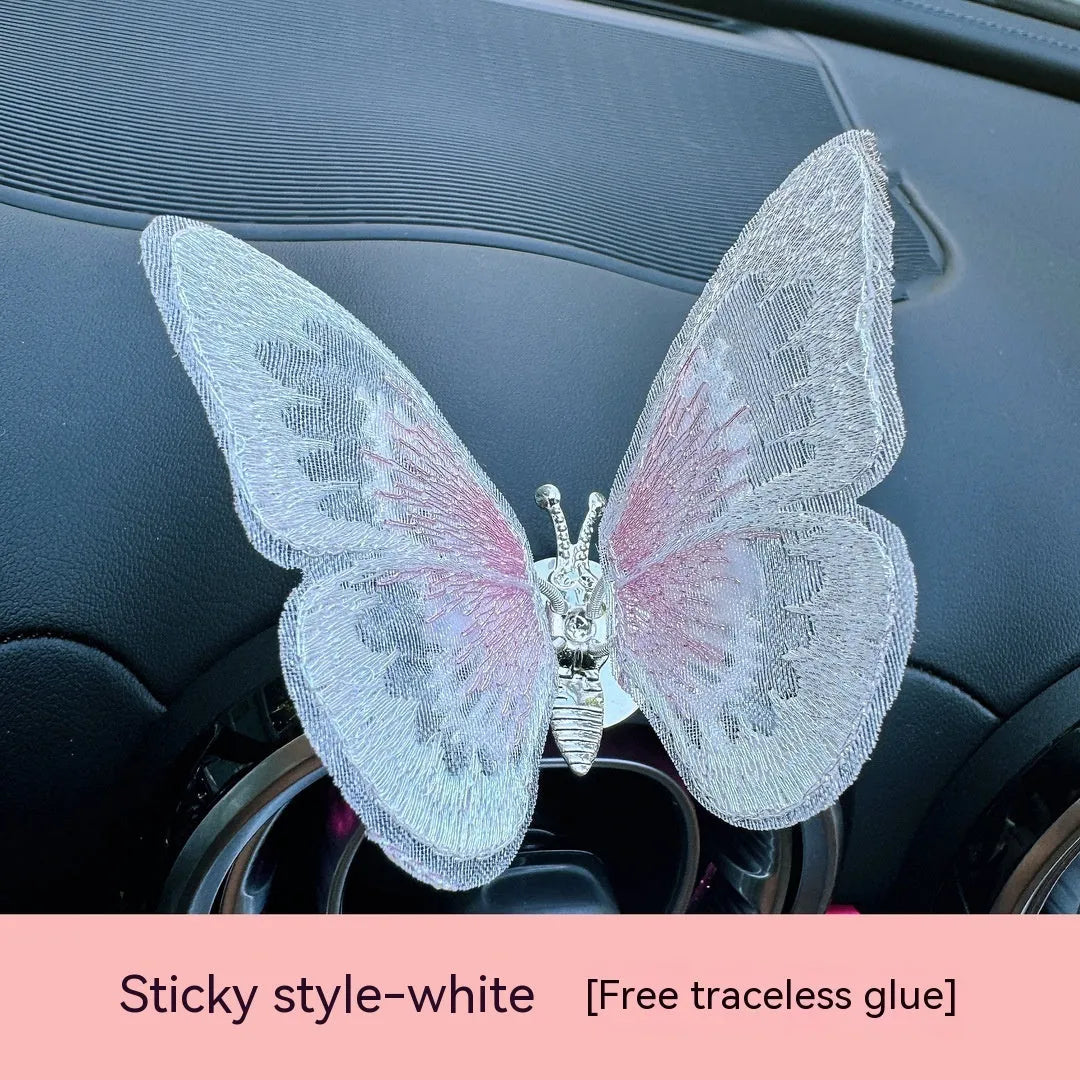 Fabric embroidered butterfly car air vent decoration in multiple colour options on a dashboard.