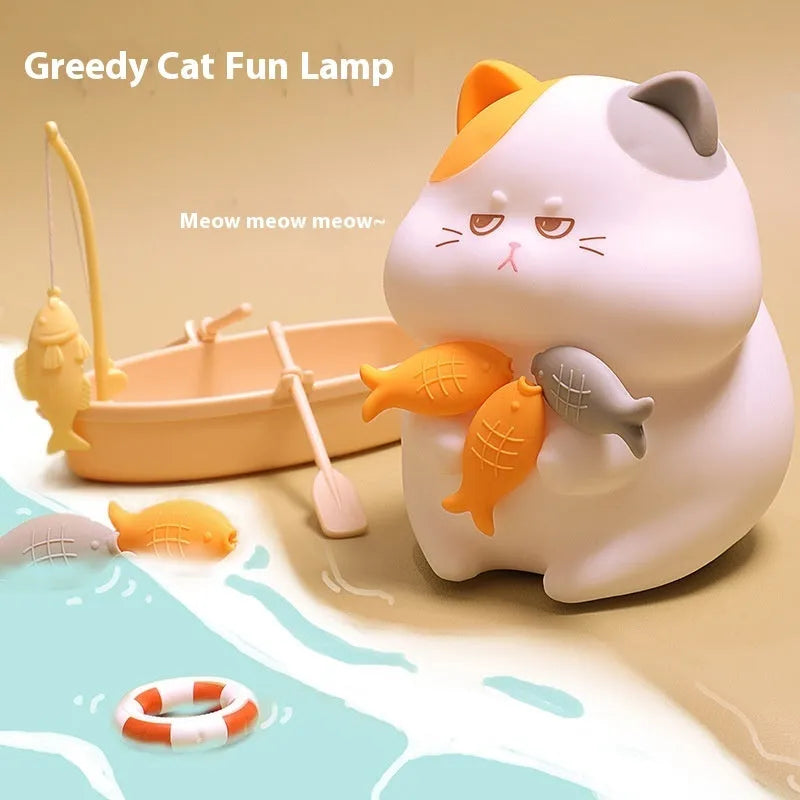 Small yellow Greedy Cat cartoon night light on a desktop, showing fish theme and compact size.