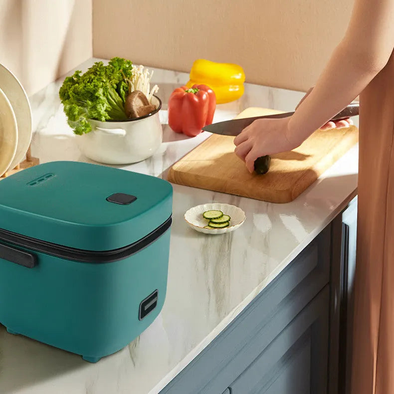 Green 1.2L mini rice cooker with metal body, steaming plate, rice spoon and measuring cup on countertop