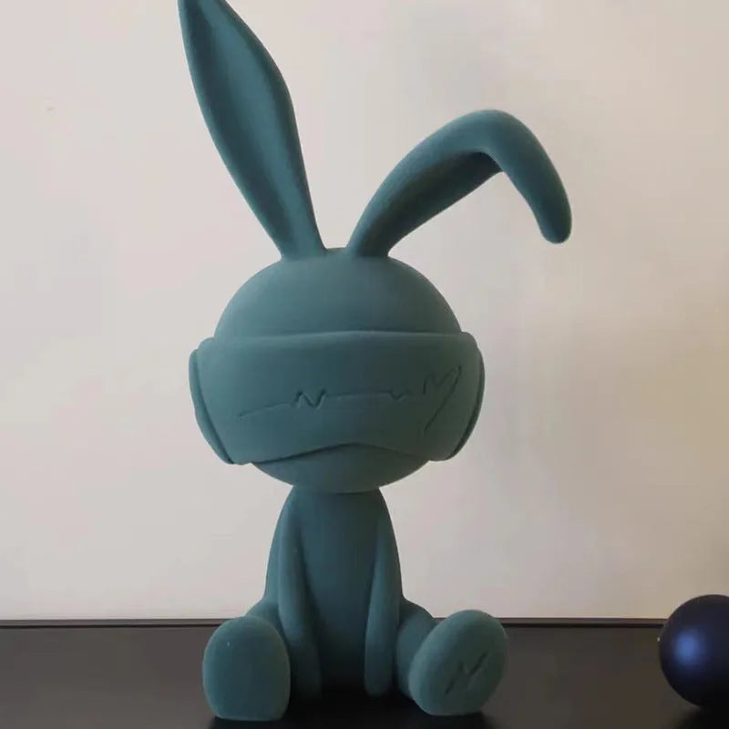 Green resin rabbit table ornament with suede blindfold on wooden surface