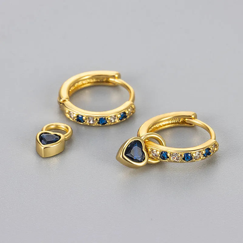 Gold colour heart-shaped clip earring with a central blue zircon stone on a white background.