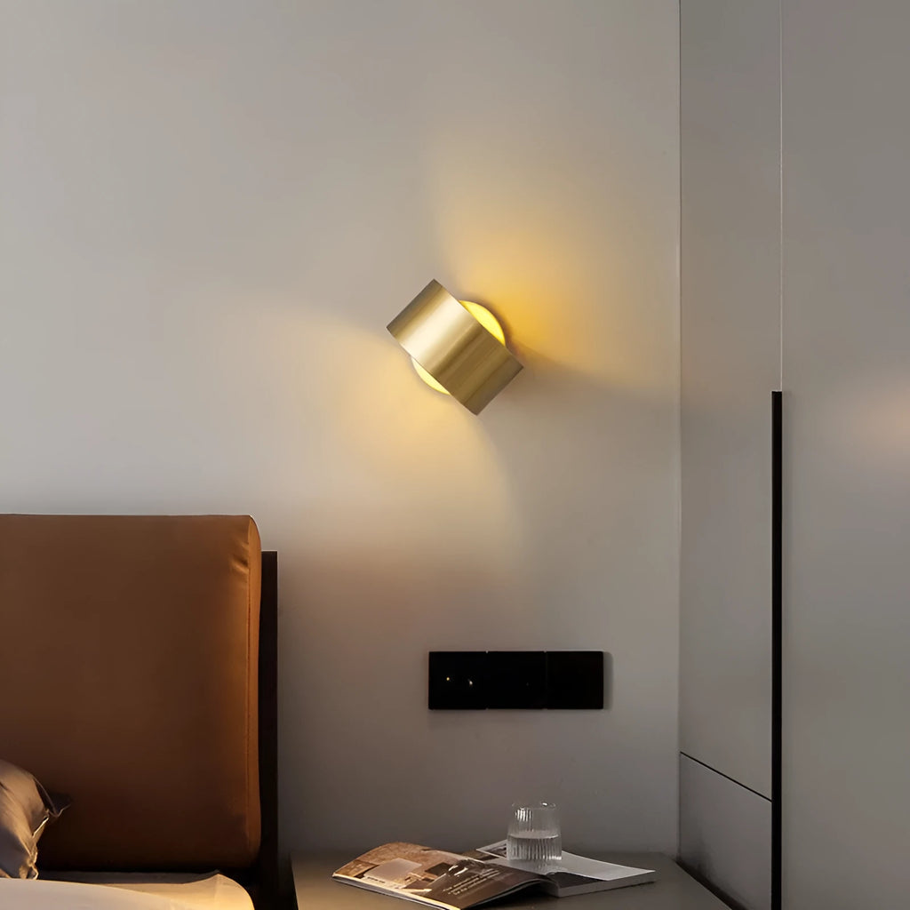 Modern minimalist copper wall lamp in gold finish mounted on a wall.