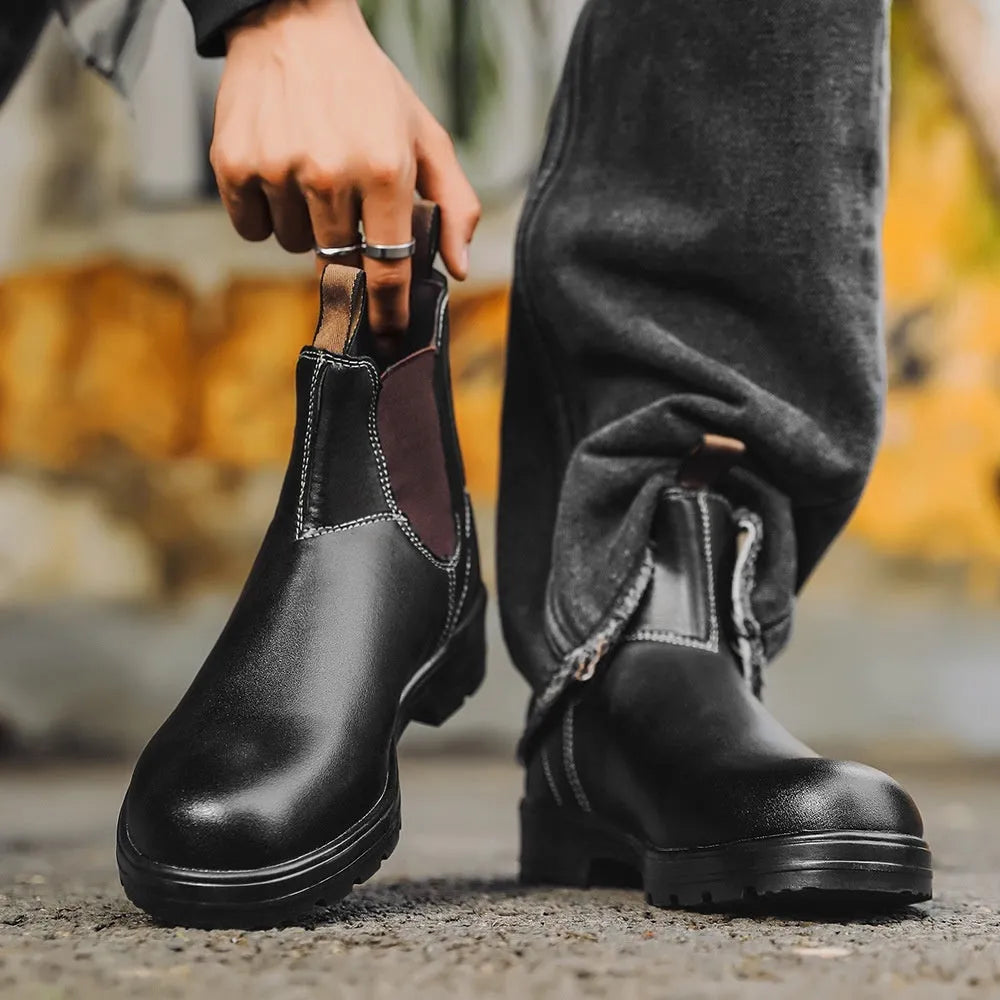 Vintage frosted brown leather Chelsea boots with round toe and car suture detailing on a wooden floor.