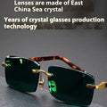 Dark green frameless crystal sunglasses inside a protective case with a lens cloth.