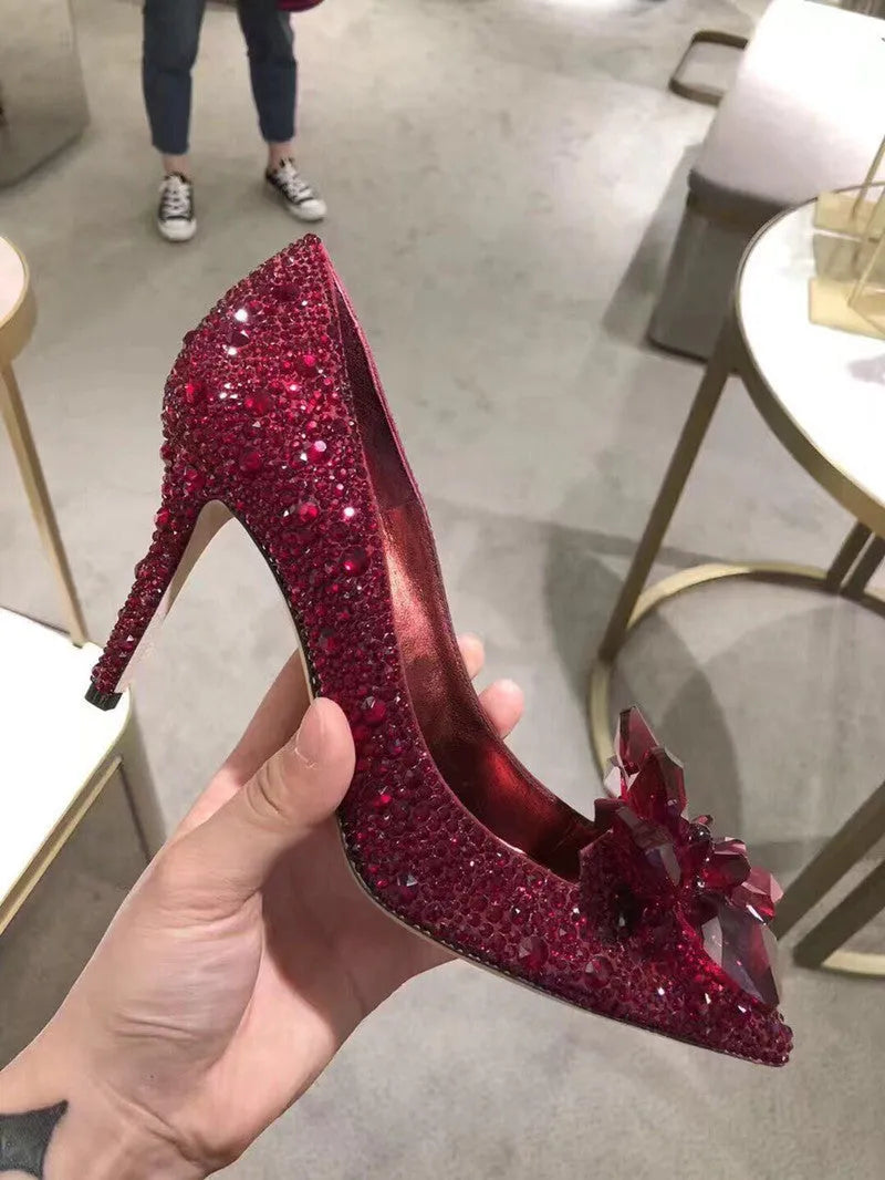 Gold women's pointed toe high heels with rhinestone and sequin decorations on a stiletto heel.