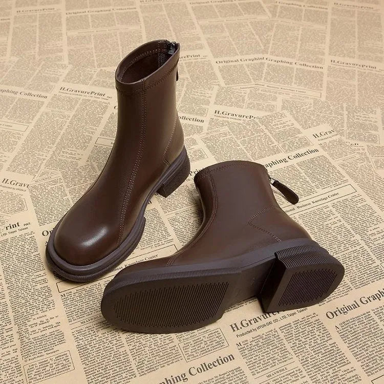 Women's black ankle boots with a flat thick heel, round toe, and rear zip fastener on a white background