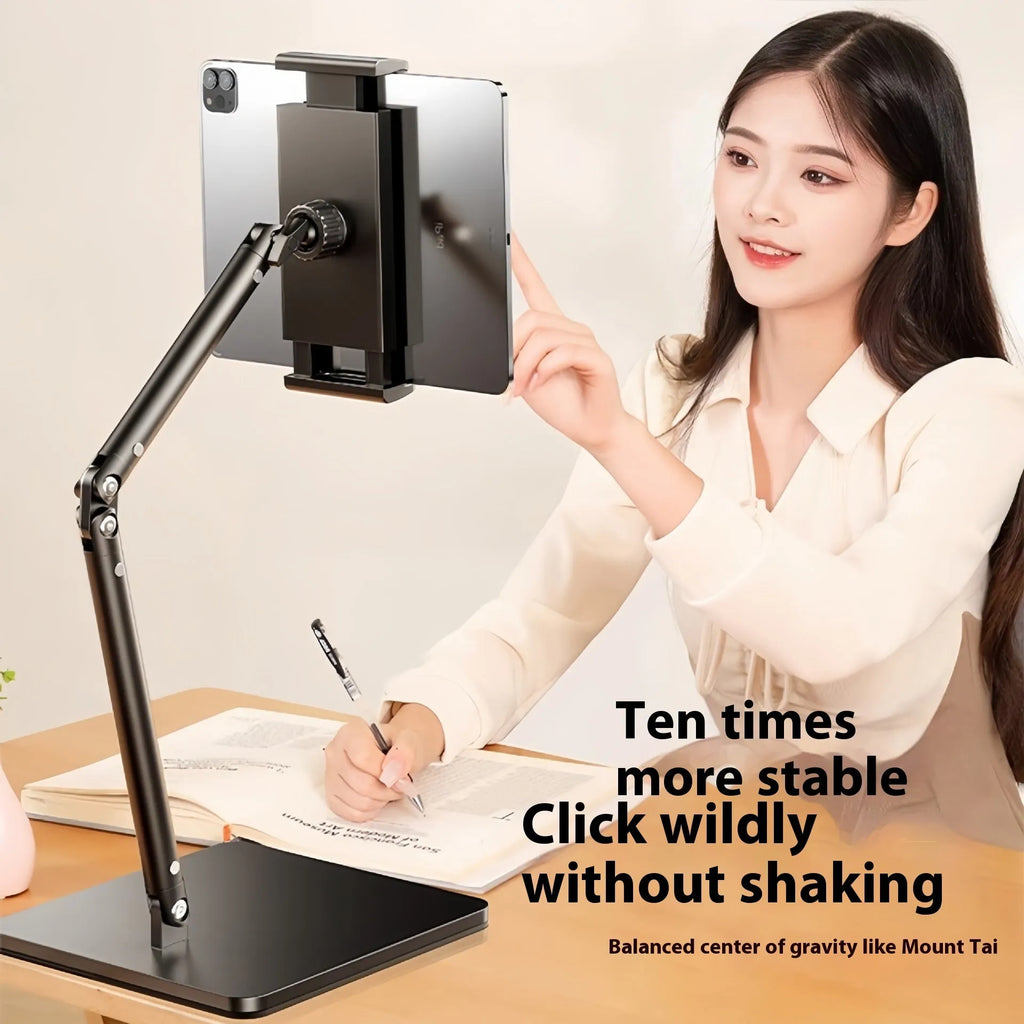 Silver alloy desktop phone and tablet bracket with double adjustable arms and a remote control on a wooden desk.