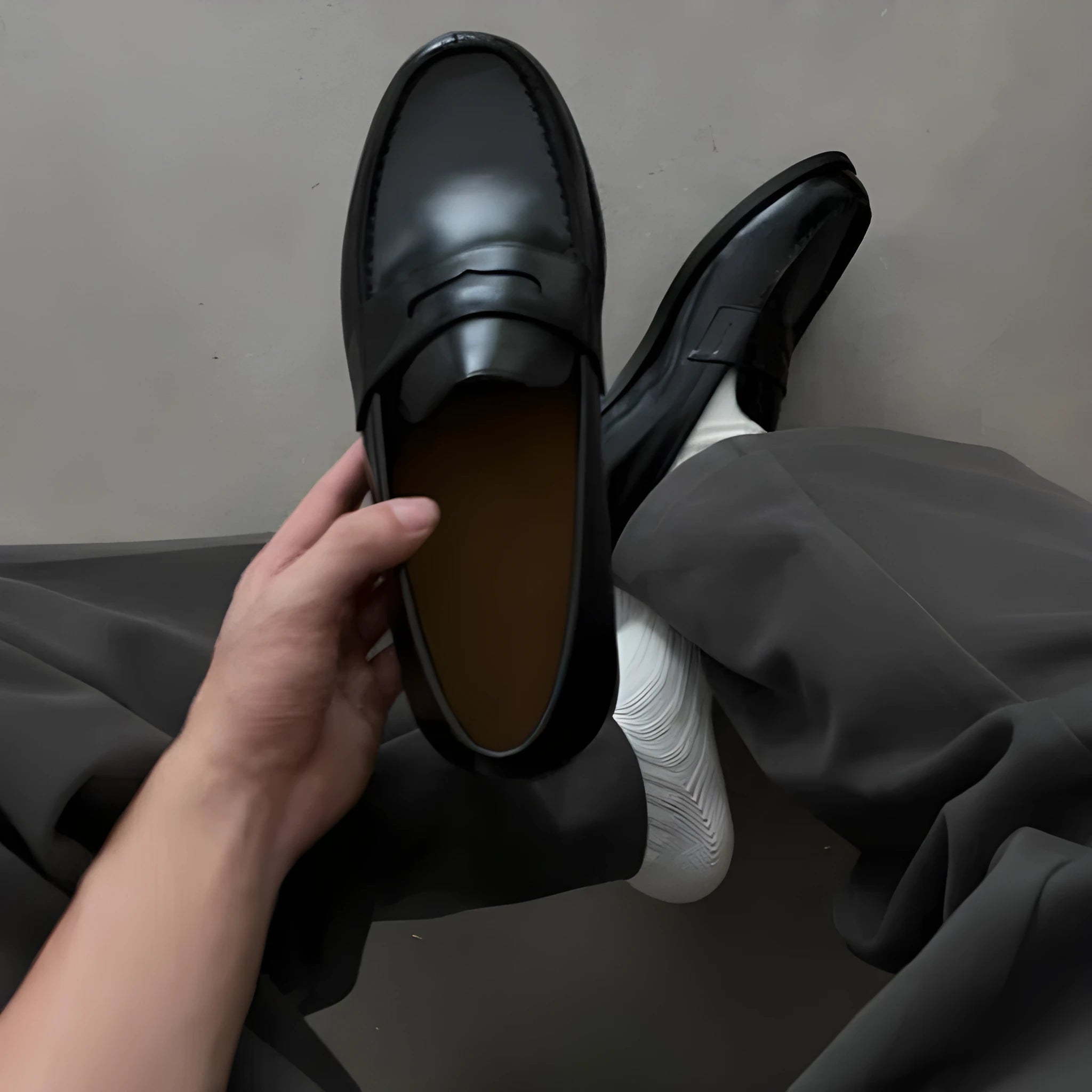 Men's black leather loafers with stitched seams, square heel, and vulcanised rubber sole on display