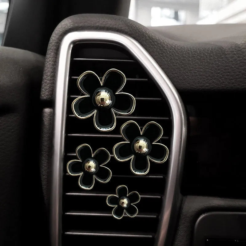 Set of four metal flower-shaped car vent aromatherapy clips in assorted colours