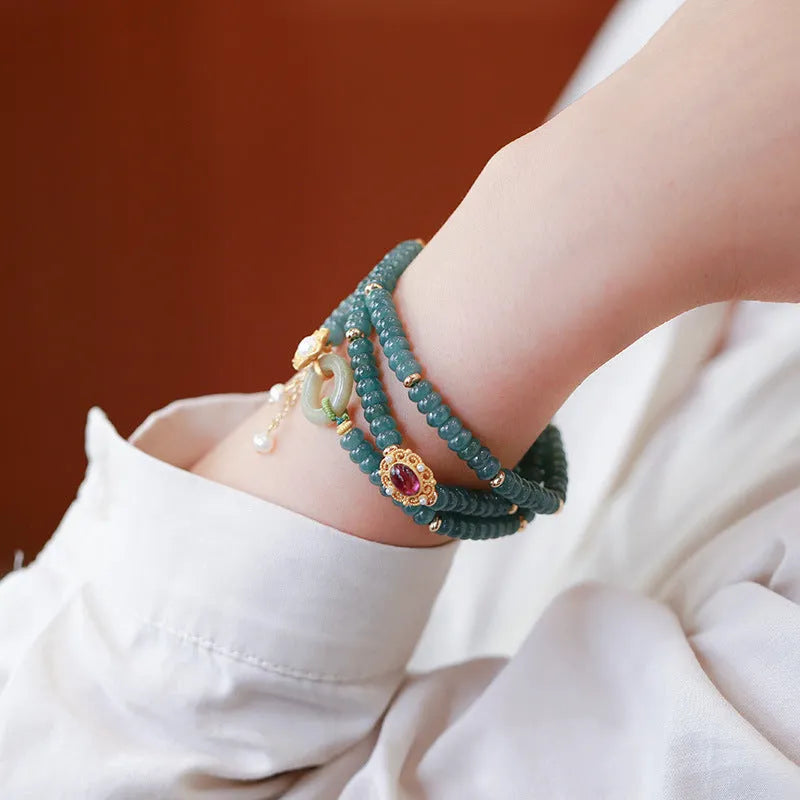 Blue water abacus and jade bead bracelet with tourmaline rings and pearl accents on a wrist.