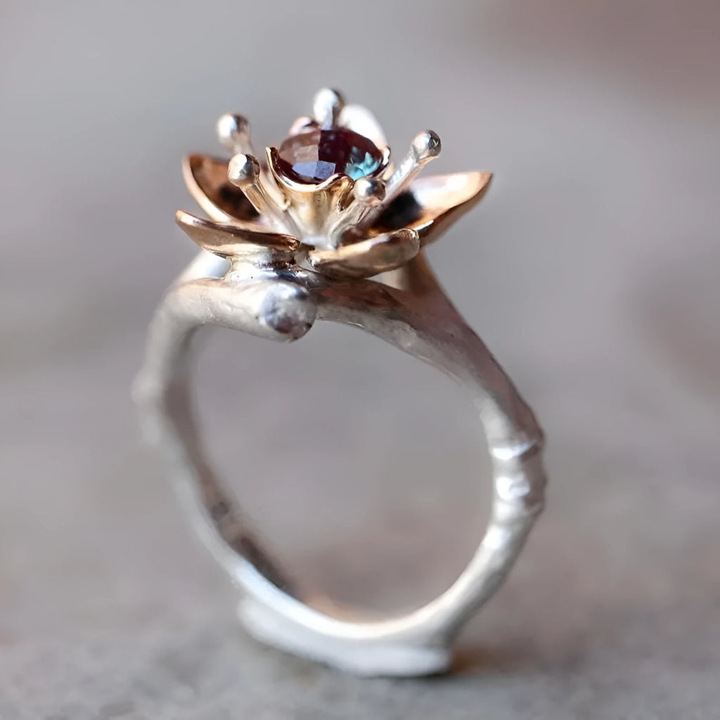 Silver two-tone women's ring with a geometric shape and floral design details on a plain background.
