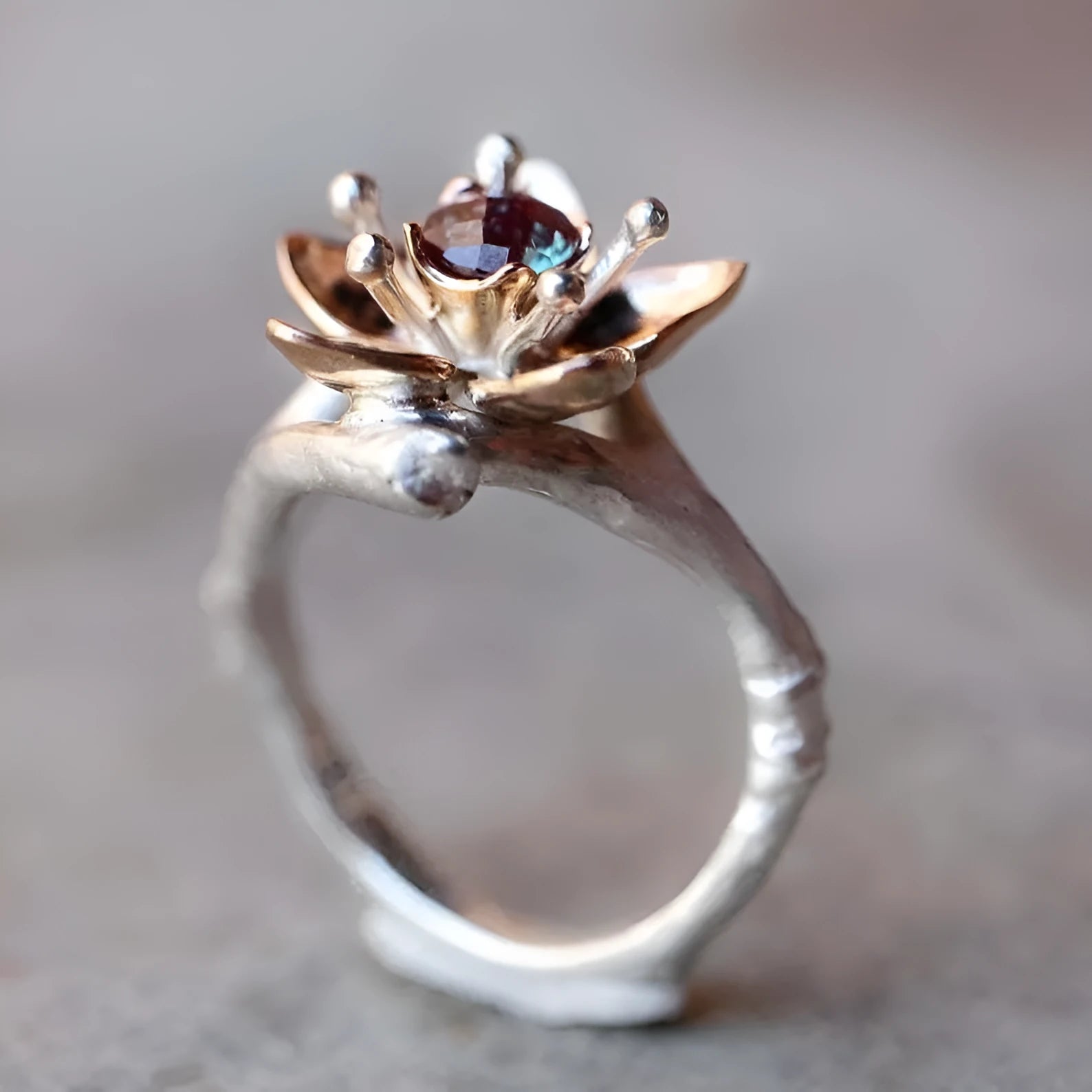 Silver two-tone women's ring with a geometric shape and floral design details on a plain background.