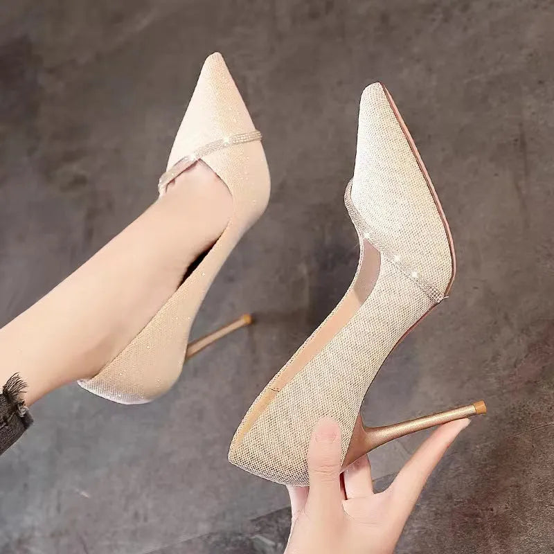 Gold women's pointed toe stiletto high heels with a low cut design on a plain background.